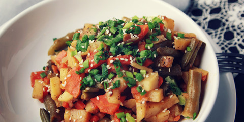 Vegetable stew with potato, carrot and green beans topped with sesame seeds. European cuisine. Healthy vegan lunch on the round white plate. European cuisine. Vegetarian. Wide photo.