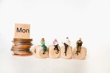 Miniature people sitting on wooden block number and stack coins background using as business concept