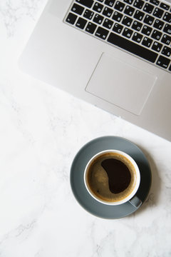 Workplace flatlay with laptop and coffee cup on marble table