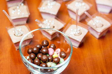 Glass bowl with dragee and multicolored jelly on  festive table_