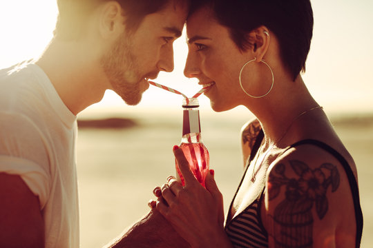 Couple in love drinking soft drink from same bottle