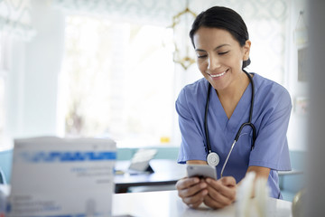 Smiling female doctor using smart phone while working in hospital