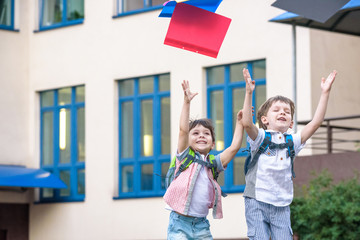 Happy children - two boys friends with books and backpacks on the first or last school day.