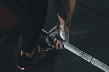 Low section of male athlete lifting barbell in health club