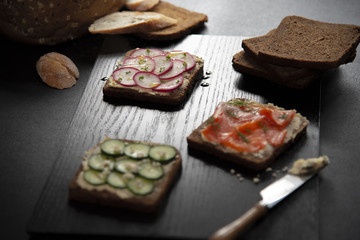 Bread made with salmon, cucumber, honey and knife placed on a wooden tray..