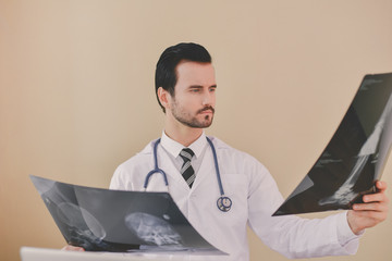 Smiling doctor posing in the office, he is wearing a stethoscope, medical staff on the hospital background