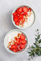 Top view on two bowls with coconut yoghurt, fresh strawberries and almonds. The concept of breakfast and a healthy lifestyle. Scandinavian style.