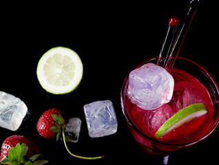 Red vodka and cranberry cocktail with white ice cubes, slice of citrus and red fresh organic...