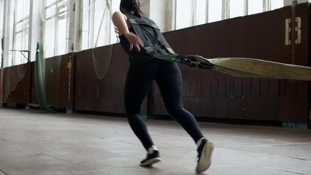 Tracking of strong woman running and pulling heavy while cross-training in empty gymnasium