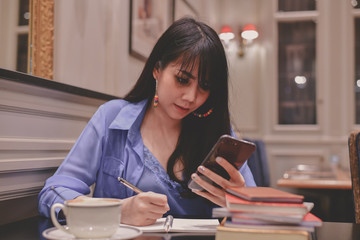 Education Concepts. Asian women are working in a restaurant. Asian women are reading a book in a restaurant.