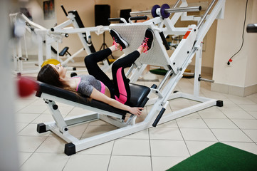 Young brunette sexy slim girl doing workout at gym.