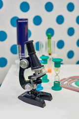 Childish optical microscope and test tubes on table in lab
