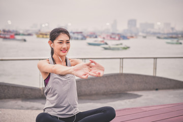Sports concept. Beautiful girl is exercising on the beach with warm up. Beautiful girl is happy to...