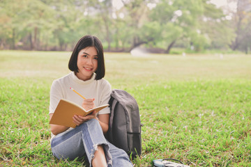 Education Concepts. Asian women reading books in the park. Beautiful women are relaxing in the park. Beautiful women are happy to read.