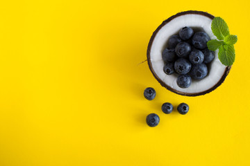 Coconut  and blueberries  on the yellow  background.Top view.