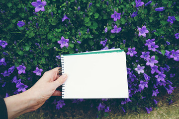 Cuaderno en blanco sobre un fondo de flores moradas