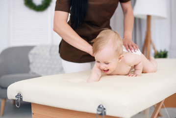 Happy baby having massage with professional female masseuse. Health care and medical concept. Kind...