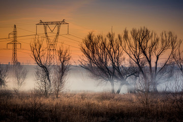 A cold winter evening nad high voltage pole. A frosty winter morning over the filds in the Lublin...