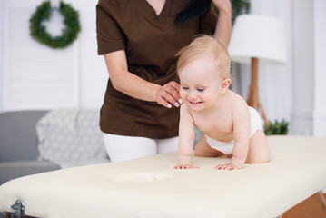 Happy baby having massage with professional female masseuse. Health care and medical concept. Kind...