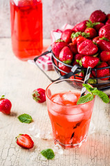 Iced strawberry drink, juice, mojito cocktail or liqueur, with fresh strawberries, light beige concrete background copy space selective focus