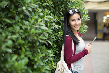 Asia woman walking and using a smart phone in the street in a sunny summer day