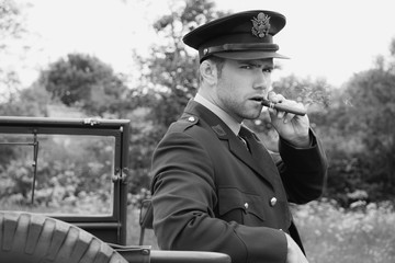 Handsome American WWII GI Army officer in uniform smoking cigar next to Willy Jeep