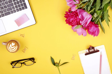 Top view of female worker desktop with laptop, flowers and different office supplies items....