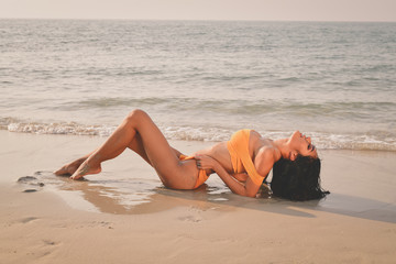 Sexy girl concept in swimsuit. Beautiful woman wearing a swimsuit playing in the beach. Girl in sexy swimsuit poses seductively. Sexy girl seduces a young man on the beach.