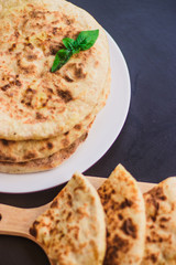 tortillas with potatoes, pita, chapati, decorated with a leaf of basil, on a black background, oriental food