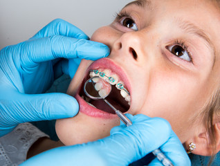 Dentist, Orthodontist examining a little girl patient's teeth