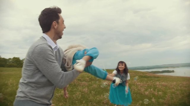 The father rolls the child on his hands, the mother lets bubbles, cloudy