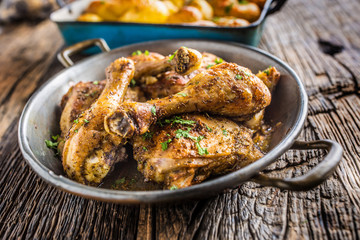 Roasted chicken legs in pan on rustic oak table