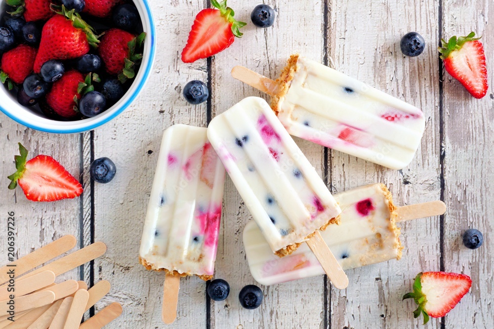 Poster group of homemade mixed berry yogurt popsicles. top view on a rustic white wood background.