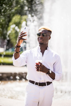 Afro american man take selfie on phone near fountain or make vidio streem live translation on summer streets