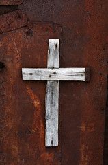 Wooden cross on a rusty door of an abandoned house