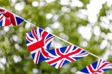 Union Jack bunting flapping in the breeze celebrating British event outside with trees in the...