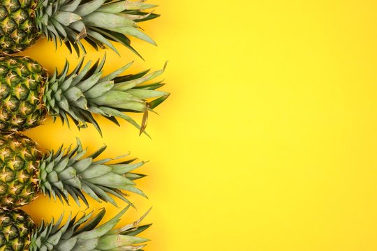 Pineapple fruit side border on a bright yellow background. Top view, flat lay with copy space.