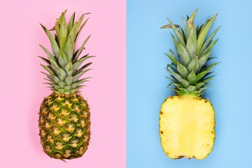 Creative pineapple layout. Whole fruit on pastel pink, half slice with blue background. Minimal summer concept Top view.