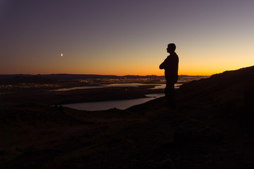 Obraz premium A man on a mountain stands overlooking Reykjavik at night in Iceland