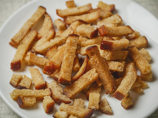 Close up of a portion of fried rye bread pieces on a white plate.