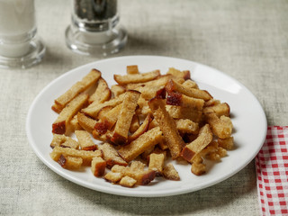 Portion of rye fried bread sticks on a white plate, salt and pepper.
