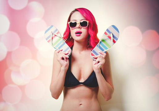 Young pink hair girl in bikini and orange glasses with flip flops. Portrait isolated on yellow background