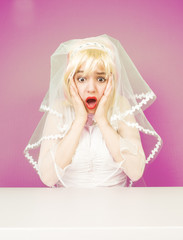 Excited beautiful blonde bride in a white dress on a pink background