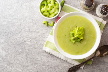 Celery cream soup in white plate on gray stone background