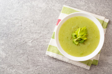 Celery cream soup in white plate on gray stone background