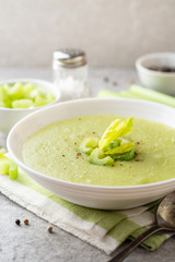 Celery cream soup in white plate on gray stone background