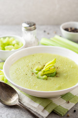 Celery cream soup in white plate on gray stone background