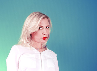 Mature woman in a white blouse on a bright background. Skeptical face. Decision making