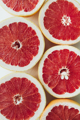 Red sliced grapefruits on white background. Flat lay, top view closeup food concept.