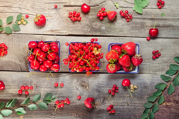 Top view Fresh summer berries - strawberry, cherry and red current in ceramic bowls on the rustic wooden table. Summer healthy diet. Farmer harvest concept. Selective focus, space for text.